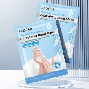 Two SADOER Goat Milk Nicotinamide Hand Mask packets displayed on a circular glass pedestal.